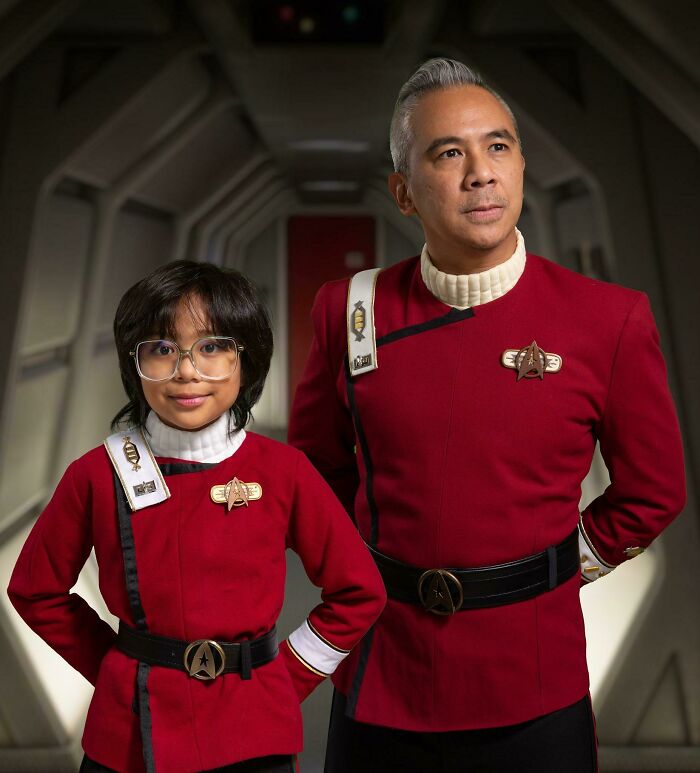 Child and adult wearing Star Trek Starfleet uniform Halloween costumes standing together.