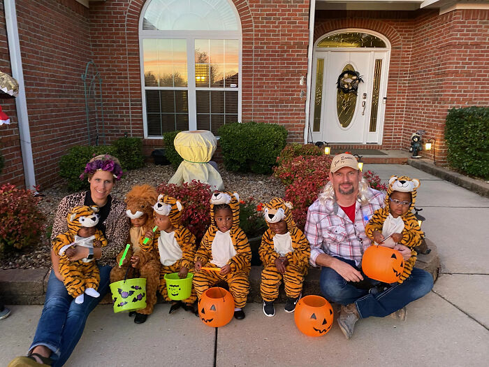 Family in Tiger King themed kids Halloween costumes sitting on a porch.