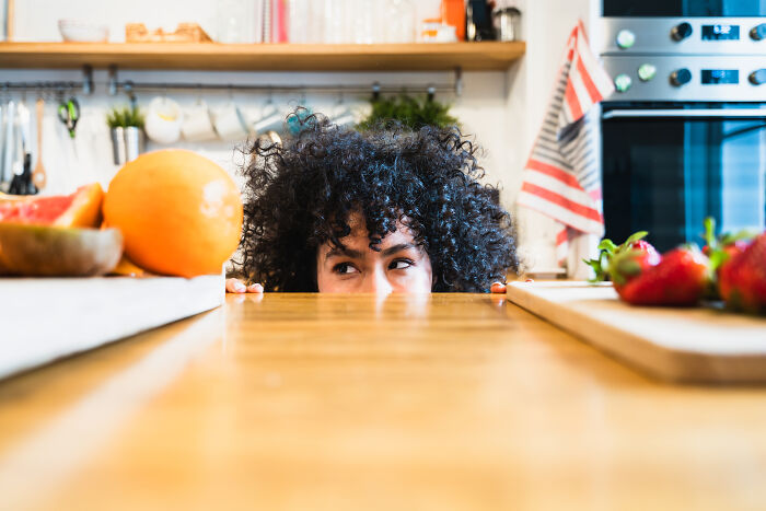 Person peeking over kitchen counter in funny haunted house story scene