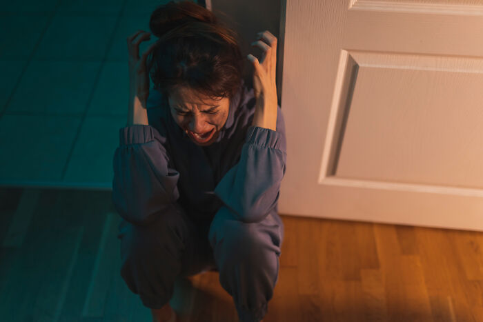 Woman crouching and screaming nervously inside a haunted house
