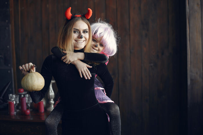 Woman and child in Halloween costumes with devil horns and face paint