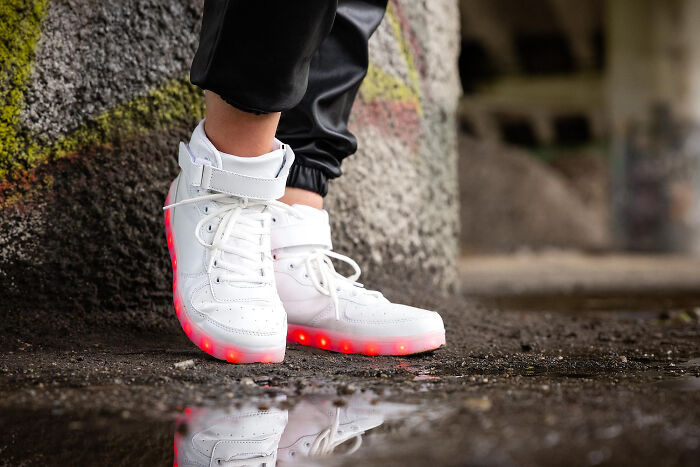 Person wearing white light-up sneakers standing near a graffiti wall indoors