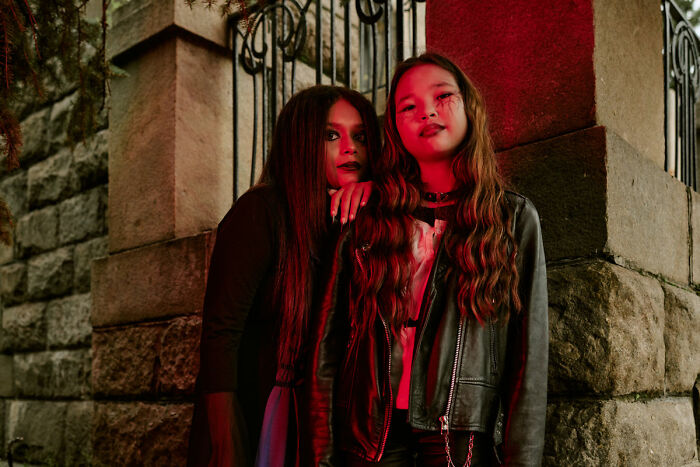 Two girls with spooky makeup posing near a haunted house entrance at night