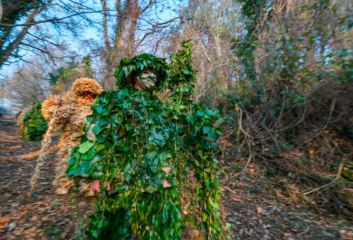 Two people dressed in leafy camouflage costumes in forest for haunted house stories