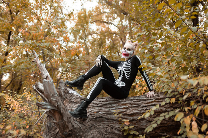 Person in skeleton costume sitting on log in autumn woods for haunted house stories