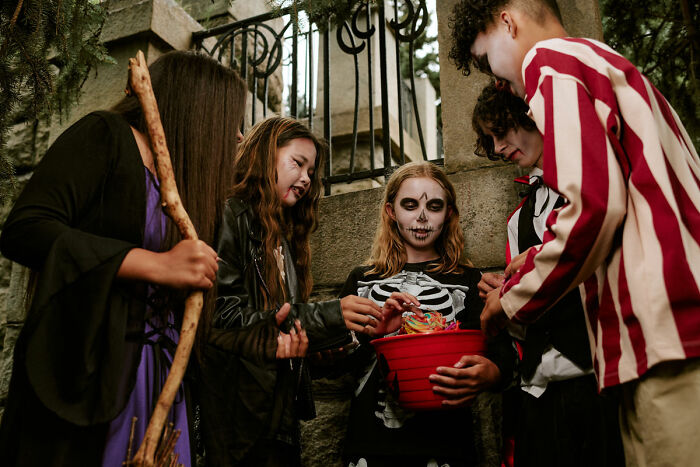 Group of kids in skeleton costumes gathering candy for haunted house stories