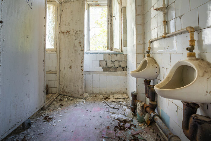 Abandoned dirty bathroom in haunted house with broken fixtures and debris on floor
