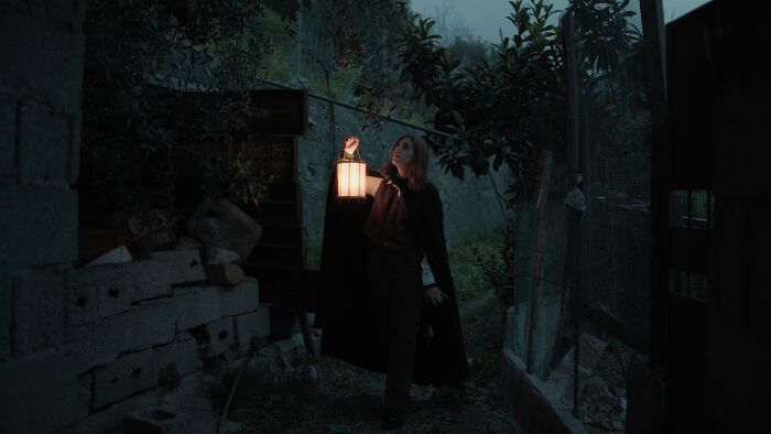 Person exploring haunted house at night holding lantern