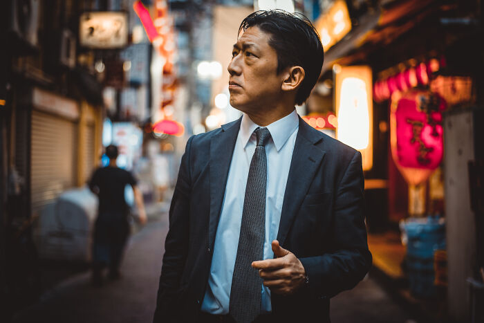 Man in suit looking around a city street at night, uneasy atmosphere