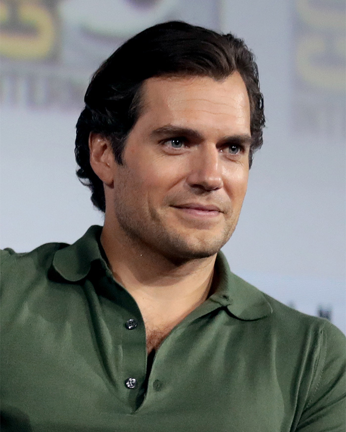An older picture of a clean-cut Henry Cavill in a green polo shirt, illustrating his five-year transformation.