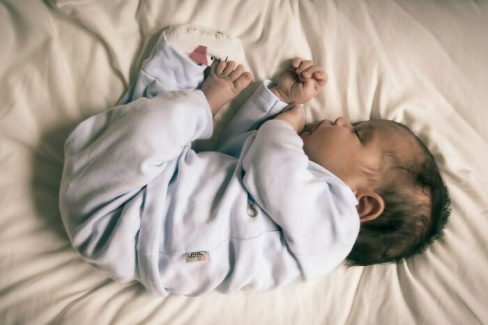 Newborn baby sleeping peacefully on cream-colored bed linens