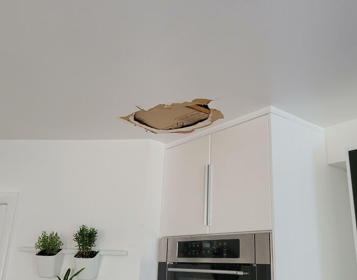 A kitchen ceiling with a large hole, demonstrating a home improvement and renovation fiasco.
