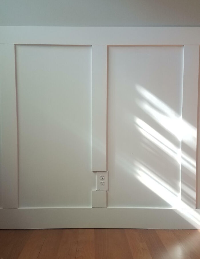 A poorly planned wainscoting home renovation showing an outlet cut into the wood panel.