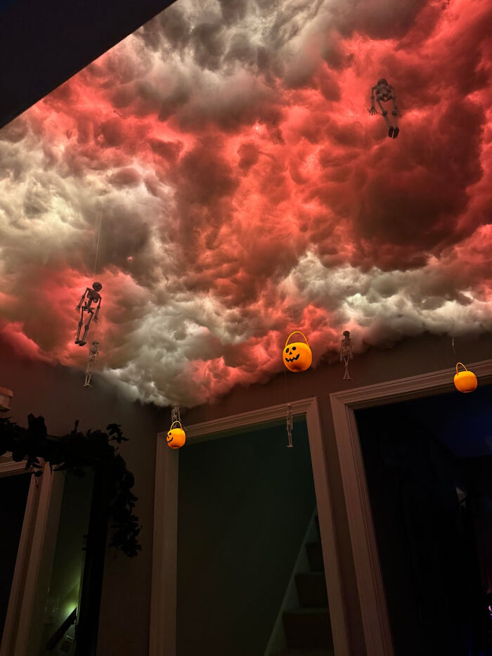 Spooky Halloween ceiling clouds illuminated with red light, skeleton figurines, and pumpkin pails
