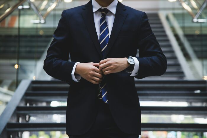 Man in business suit adjusting tie symbolizing wealthy professionalism