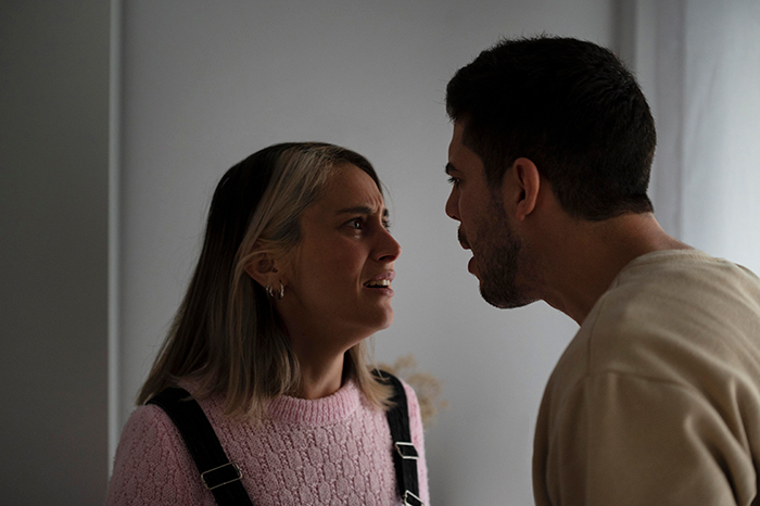 Woman in pink sweater confronting man in tense moment