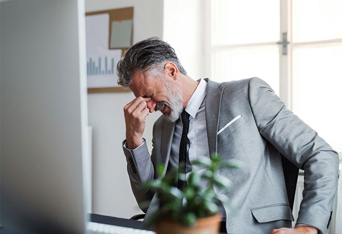 A stressed middle-aged husband in a grey suit rubbing his forehead at his desk, overwhelmed by his wife's demands. A stressed middle-aged husband in a grey suit rubbing his forehead at his desk, overwhelmed by his wife's demands.
