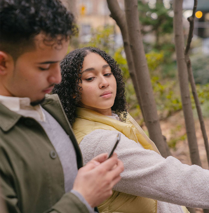A suspicious wife looking over her husband's shoulder as he uses his phone to test his integrity. A suspicious wife looking over her husband's shoulder as he uses his phone to test his integrity.