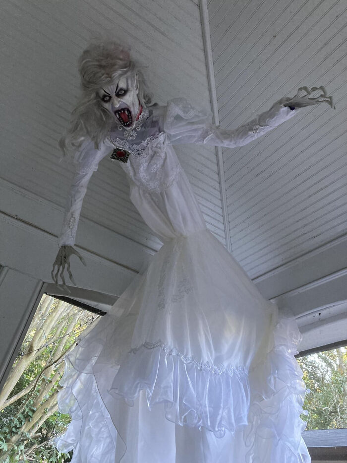 Spooky ghost bride decor hanging from a porch for Halloween.