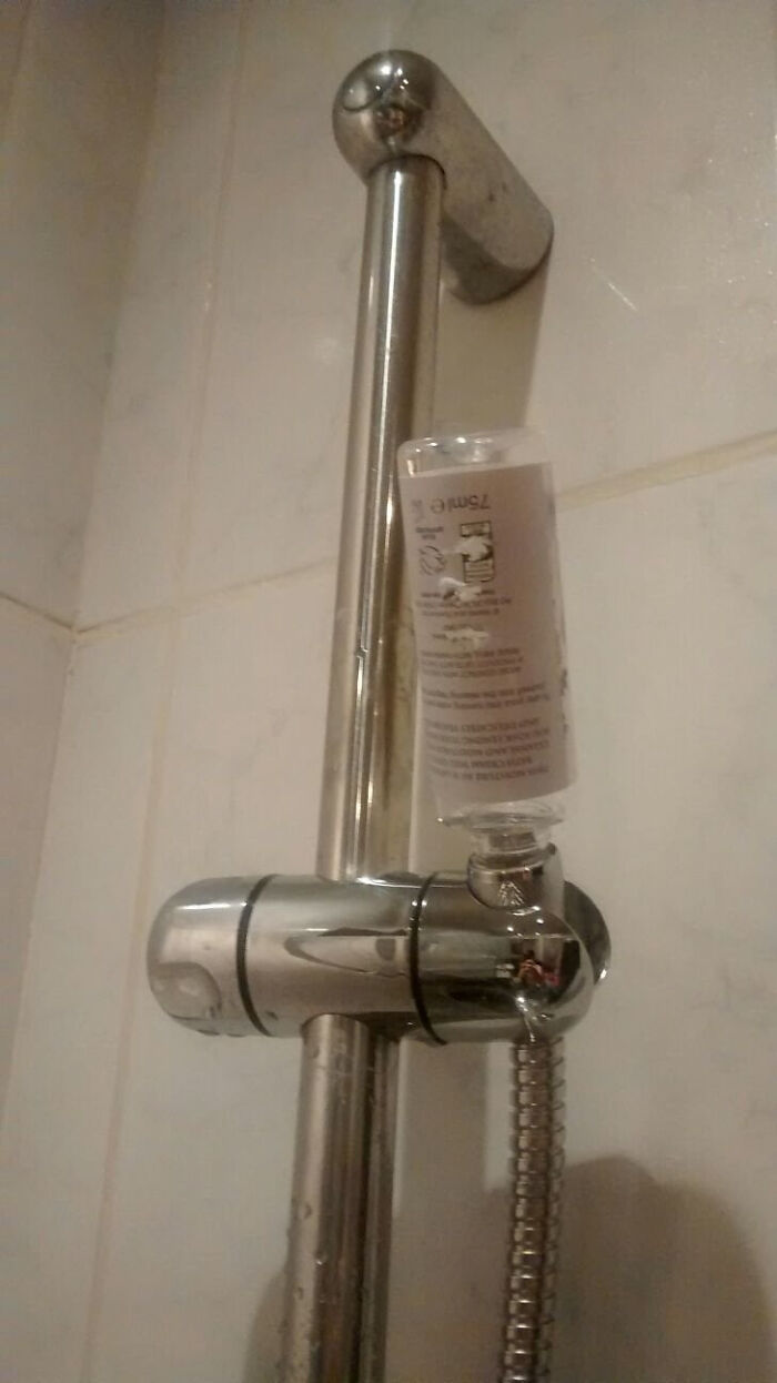 A shower head holder with a plastic bottle used as a makeshift repair, demonstrating a home renovate fail