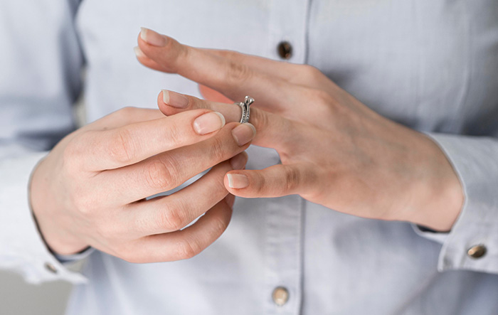 A woman taking off a wedding ring, symbolic of a family heirloom ring being returned A woman taking off a wedding ring, symbolic of a family heirloom ring being returned