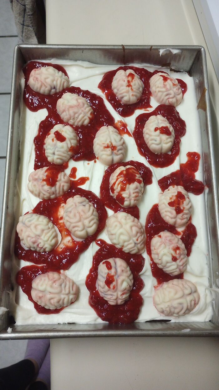 A tray of spooky Halloween foods shaped like gory white brains swimming in bloody red fruit sauce.