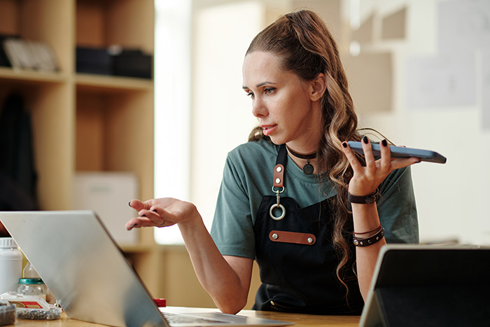 A retail employee gesturing in confusion while working on a laptop. A retail employee gesturing in confusion while working on a laptop.