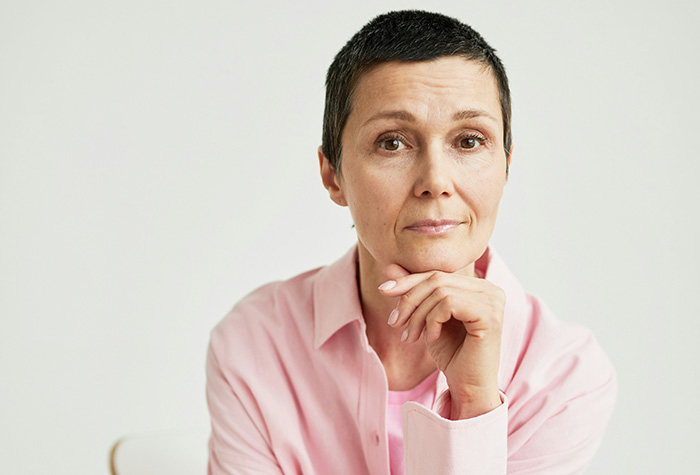 A thoughtful woman in a pink shirt representing a woman holding a family heirloom. A thoughtful woman in a pink shirt representing a woman holding a family heirloom.