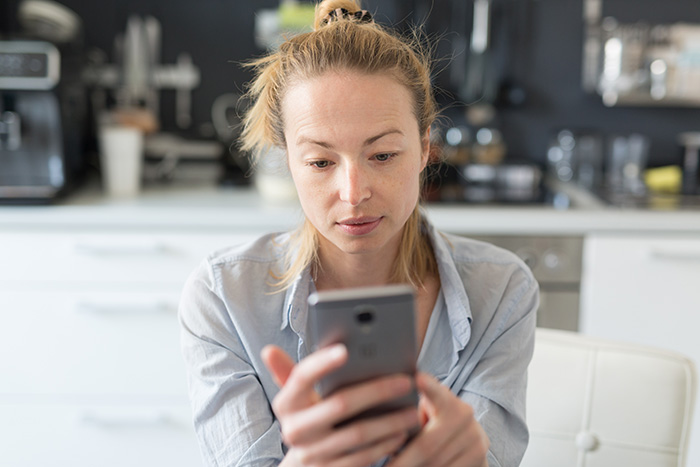 A worried woman holding a smartphone, looking distressed about an aunt leaving her niece at school drama. A worried woman holding a smartphone, looking distressed about an aunt leaving her niece at school drama.
