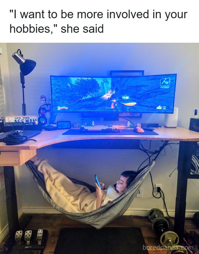 A woman rests in a hammock under a gaming desk while her partner plays, featured in silly and fun posts online.