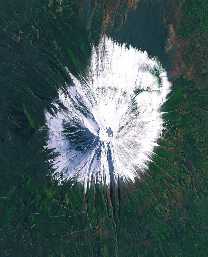 Surreal satellite photo looking straight down at snow-capped Mount Fuji.