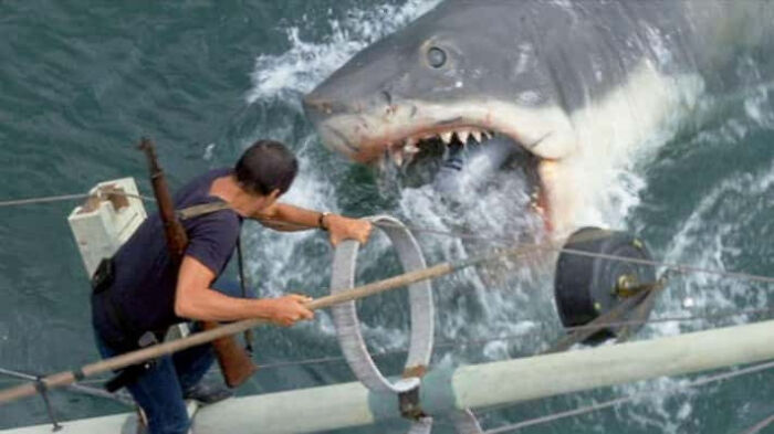 A mechanical shark movie prop attacking a boat in a vintage action film scene