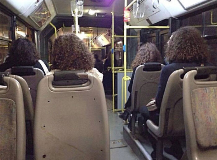 Four people with identical curly hair seated on a bus glitch
