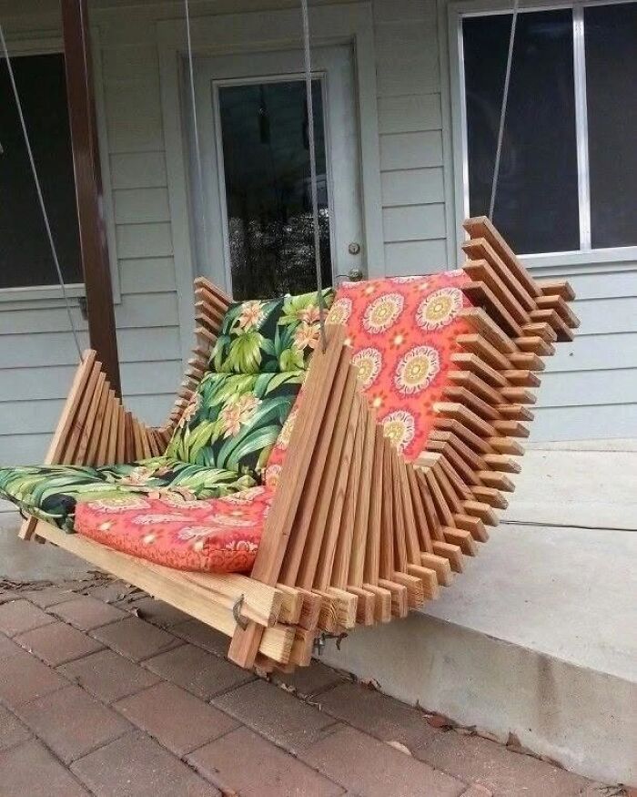 A modern outdoor swinging bench, one of many clever wooden creations, with vibrant floral cushions.