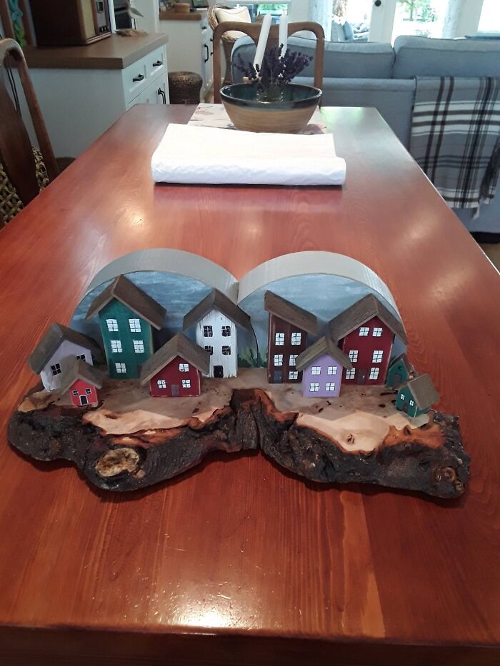 Charming wooden creations of small, colorful model houses arranged on a natural wood base.