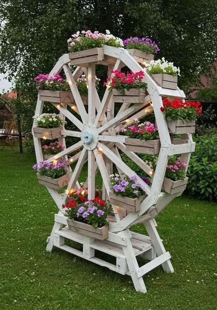 A decorative white ferris wheel planter in a garden, showing clever wooden creations
