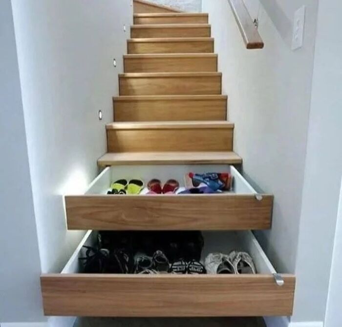 Under-stairs storage drawers pulled out to show shoes, demonstrating clever wooden creations for space-saving.