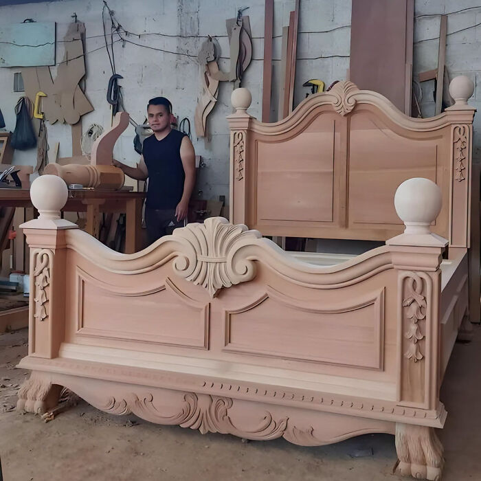 Carved wooden bed frame in a workshop, showcasing ornate wooden creations crafted by an artisan.