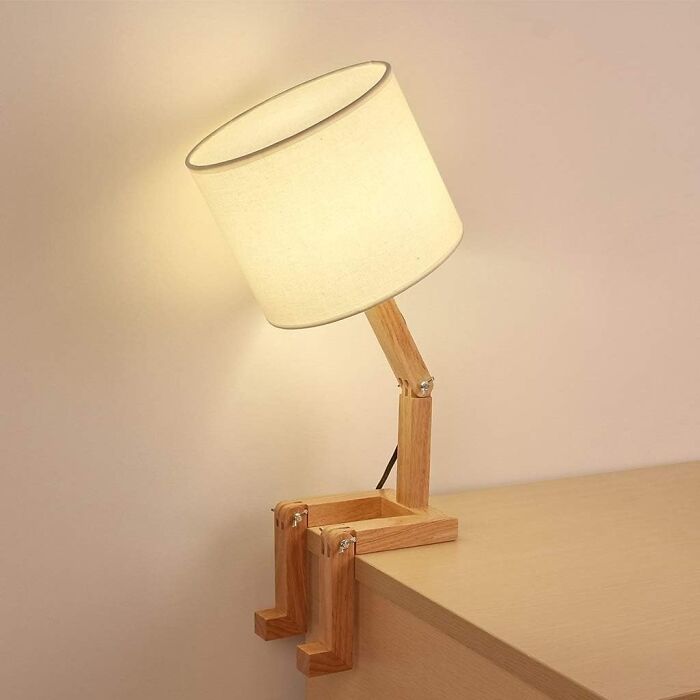A human-shaped wooden desk lamp sitting on the edge of a table.
