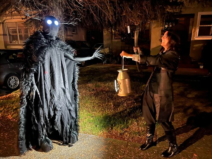 Two people in dark fantasy monster costumes holding a lantern, demonstrating funny cool Halloween couples costumes.