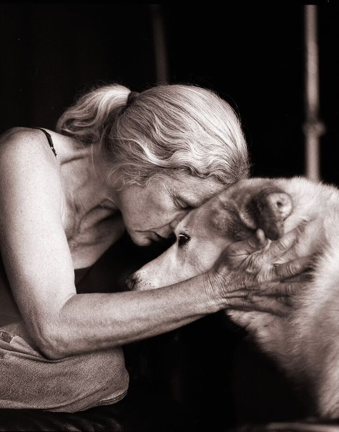 An intimate portrait photo showing a loving connection with a woman leaning her forehead against her dog