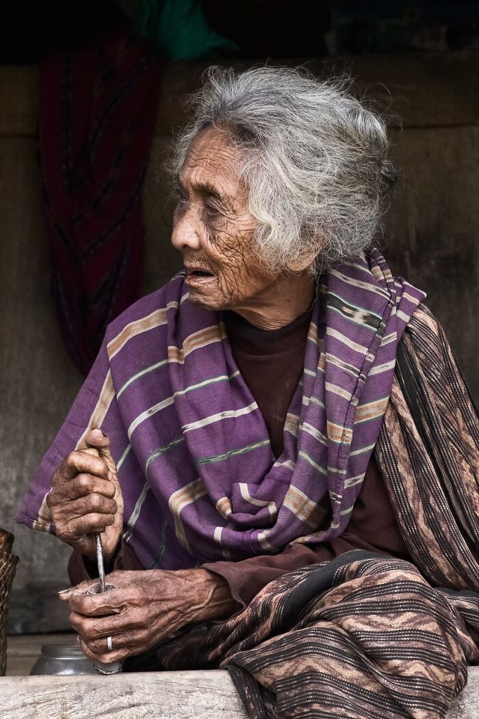 A portrait photo showing the deep expression of an elderly woman holding a tool while looking away