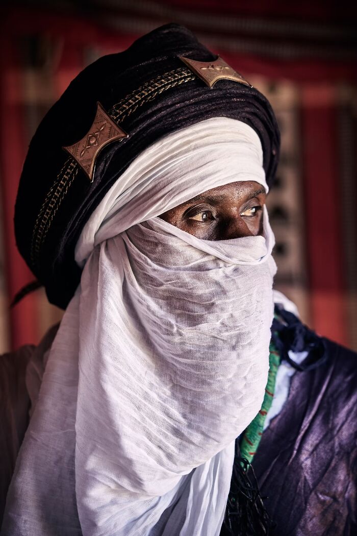 A portrait photo of a Tuareg man in a traditional white turban and veil looking aside