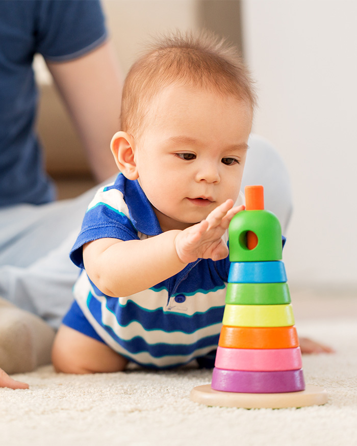 A baby playing with a colorful stacking ring toy, illustrating early child development and Beige Mom debates. A baby playing with a colorful stacking ring toy, illustrating early child development and Beige Mom debates.