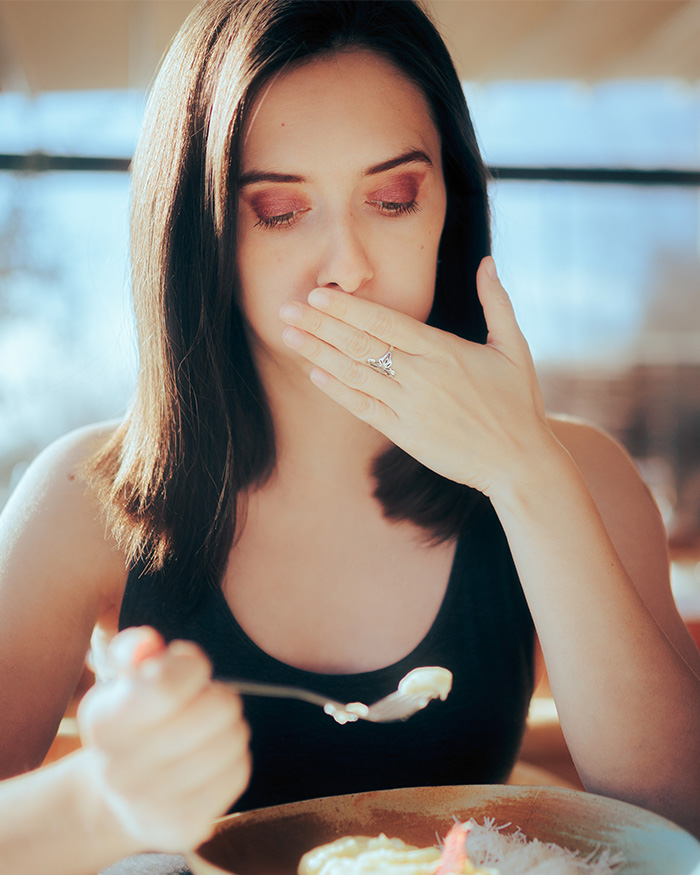 Woman feeling nauseous while eating, illustrating the risks of eating sushi.