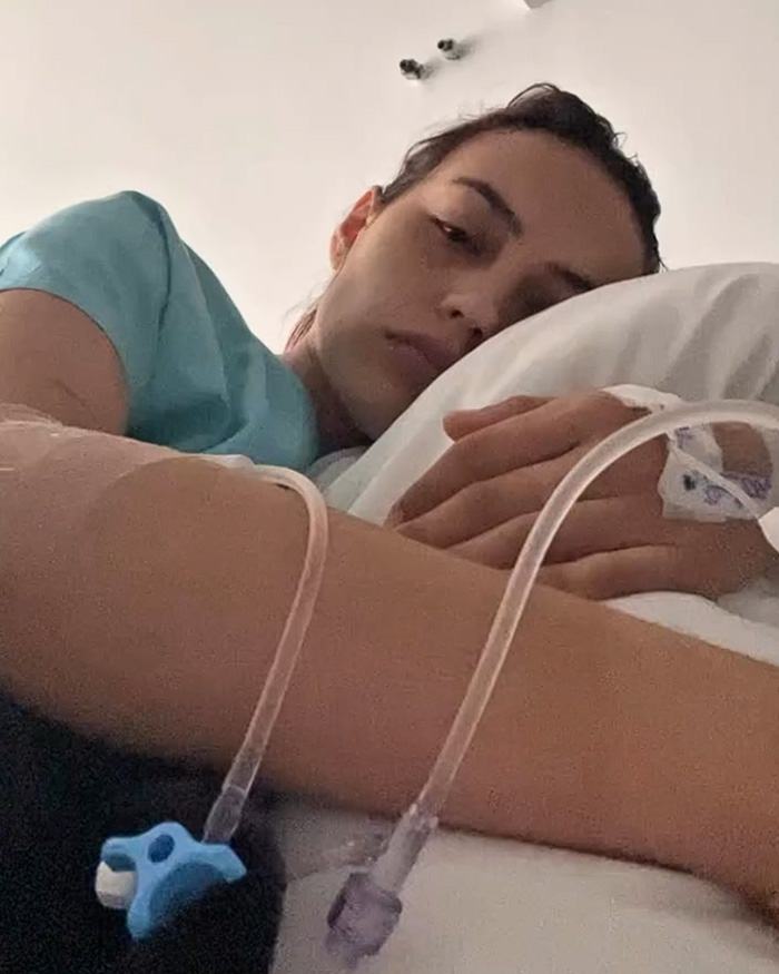 A young influencer resting in a hospital bed with an IV drip after facial paralysis and ICU stay. A young influencer resting in a hospital bed with an IV drip after facial paralysis and ICU stay.