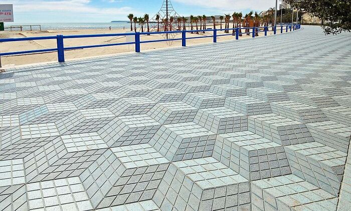 A seaside promenade in Spain decorated with a geometric 3D cube pattern pavement