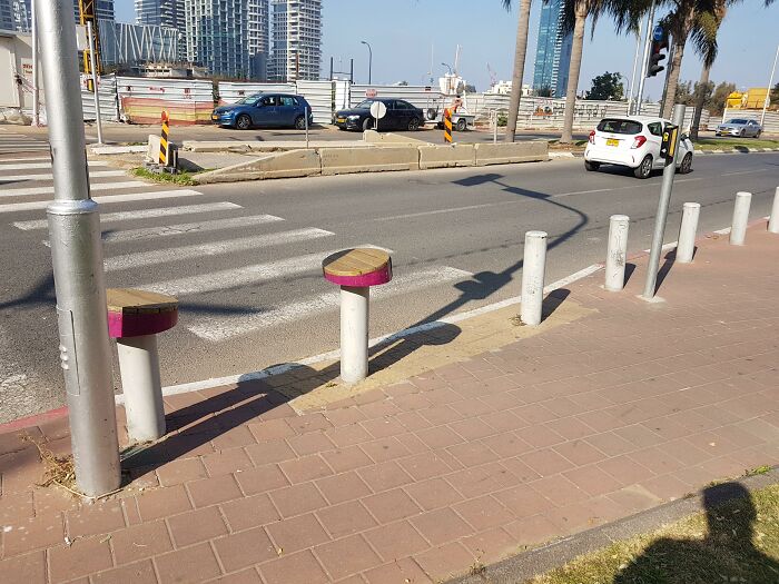 Ingenious things in urban design: street bollards topped with wooden seats for pedestrians.