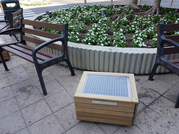 Useful and ingenious things in public park: a solar-powered wooden charging station next to benches.