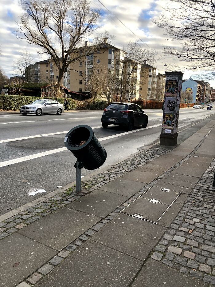 An angled trash can on a city sidewalk showing ingenious things in various parts of the world for cyclists.